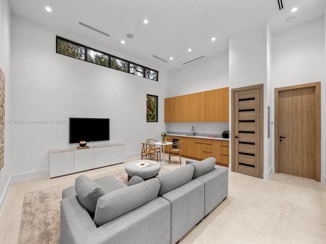 living area with baseboards, a high ceiling, visible vents, and recessed lighting