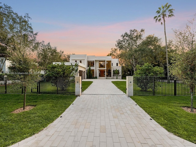 view of front facade with a fenced front yard, decorative driveway, a gate, stucco siding, and a front lawn