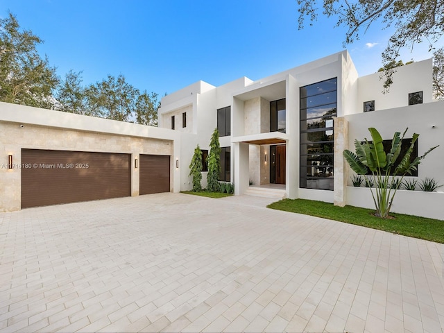 view of front facade featuring a garage, decorative driveway, and stucco siding