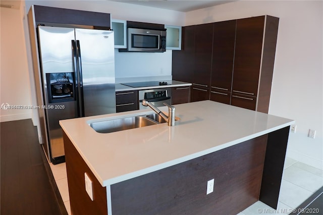 kitchen with dark brown cabinetry, sink, a center island with sink, and appliances with stainless steel finishes