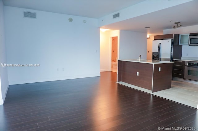 kitchen featuring dark brown cabinetry, sink, stainless steel appliances, dark hardwood / wood-style floors, and a kitchen island