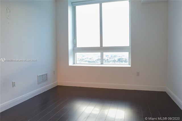 spare room with dark hardwood / wood-style flooring and plenty of natural light