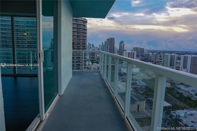 balcony at dusk featuring a water view