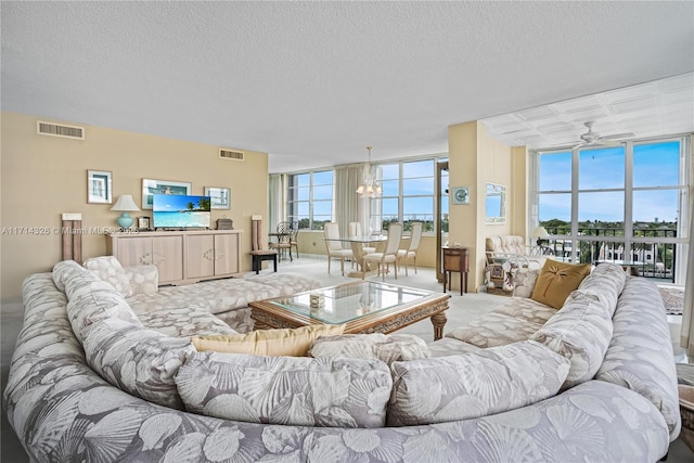 living room featuring a textured ceiling, carpet, and ceiling fan with notable chandelier