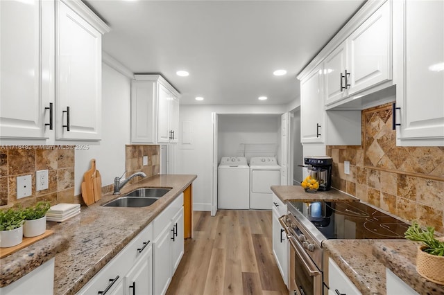 kitchen with high end stove, sink, white cabinets, and independent washer and dryer