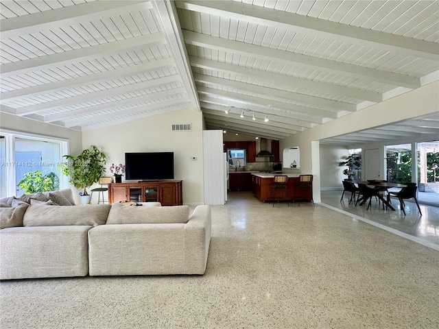 living room with vaulted ceiling with beams and plenty of natural light