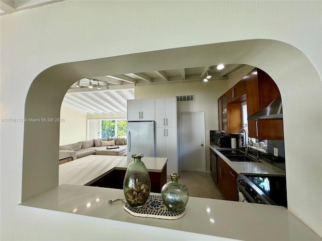 kitchen with stainless steel refrigerator, white cabinetry, range with electric cooktop, sink, and wall chimney exhaust hood