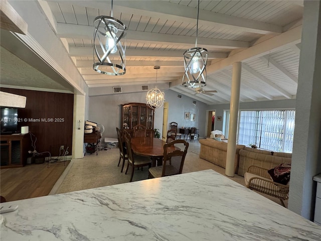 dining area featuring vaulted ceiling with beams, ceiling fan, and wooden walls