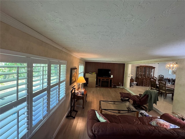 living room featuring a chandelier, wood-type flooring, a textured ceiling, and crown molding