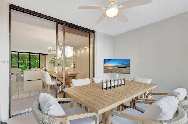 dining space with ceiling fan with notable chandelier, a wall of windows, and a textured ceiling