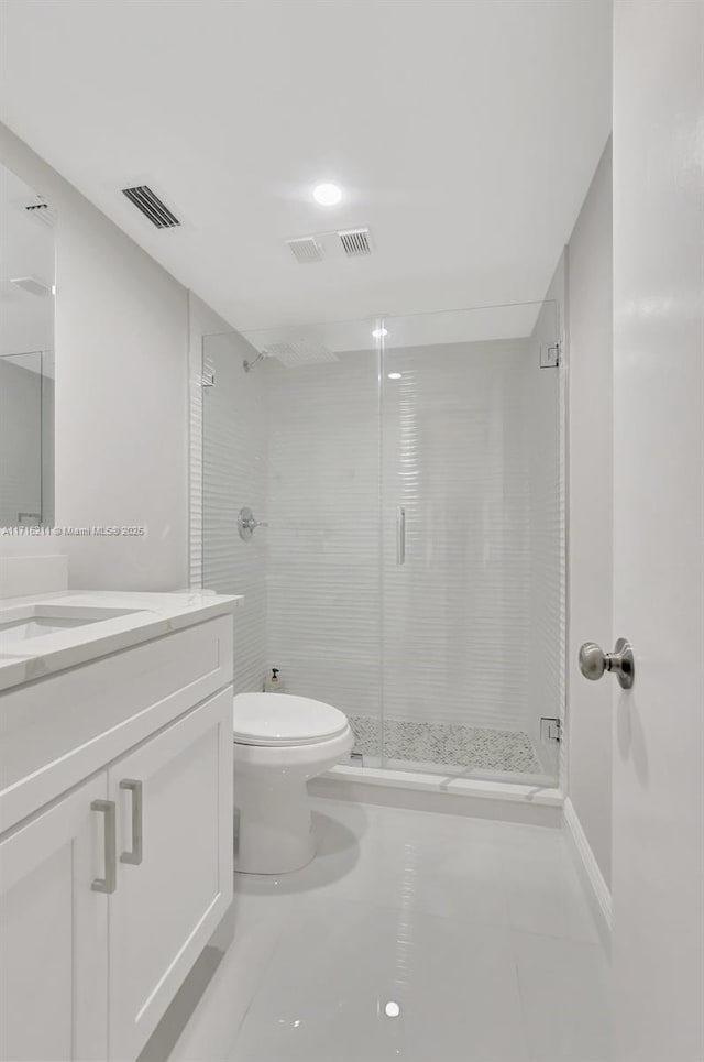 bathroom featuring tile patterned floors, vanity, toilet, and a shower with door