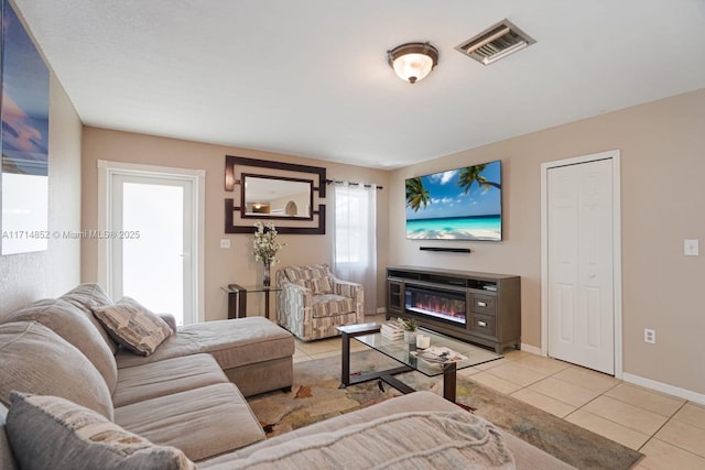 tiled living area featuring visible vents, baseboards, and a glass covered fireplace