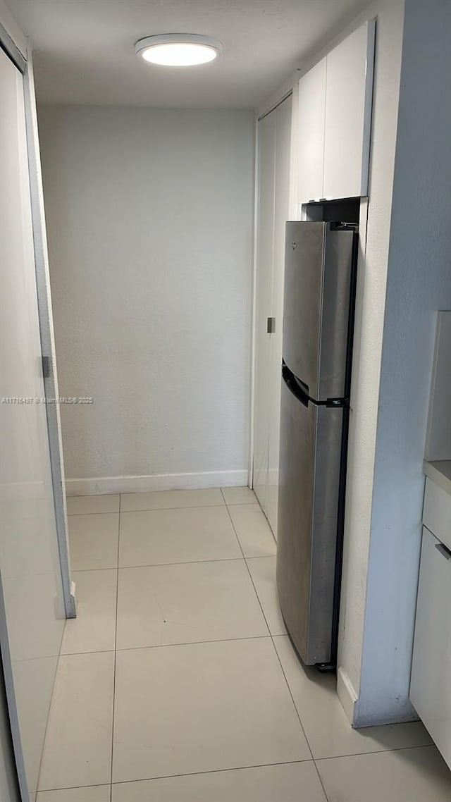 kitchen with light tile patterned floors, white cabinetry, and stainless steel refrigerator