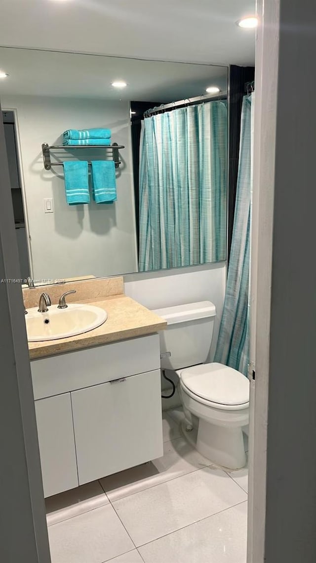 bathroom with tile patterned flooring, vanity, toilet, and walk in shower