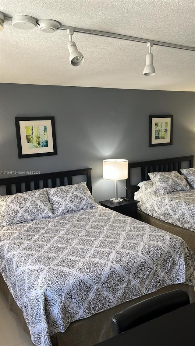 bedroom featuring a textured ceiling and track lighting