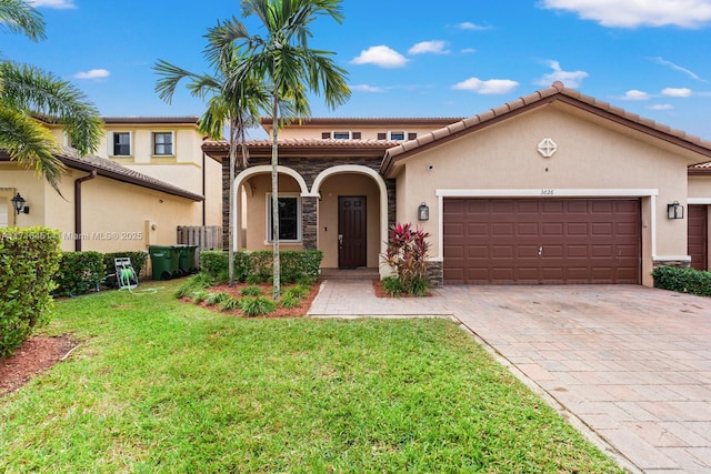 mediterranean / spanish-style home with a front yard, an attached garage, and stucco siding