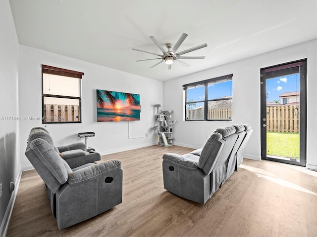 living area with ceiling fan, light wood finished floors, and baseboards