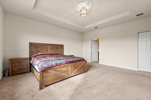 bedroom featuring a tray ceiling, baseboards, visible vents, and carpet flooring