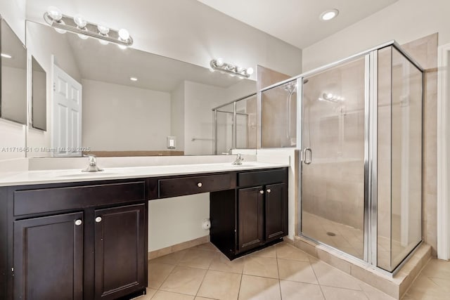 full bathroom featuring double vanity, a stall shower, a sink, and tile patterned floors