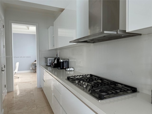 kitchen featuring gas cooktop, white cabinets, and wall chimney exhaust hood