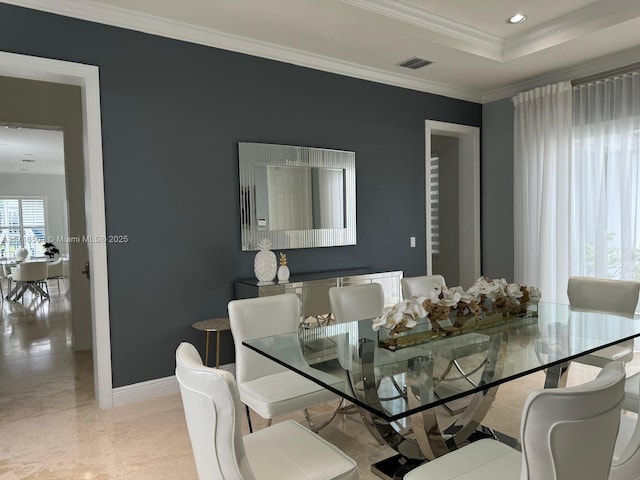 dining space with a raised ceiling and ornamental molding