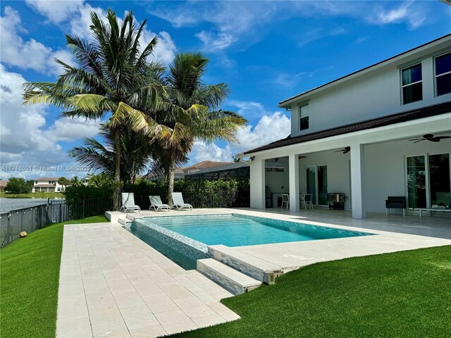 view of swimming pool featuring ceiling fan, a patio, and a lawn