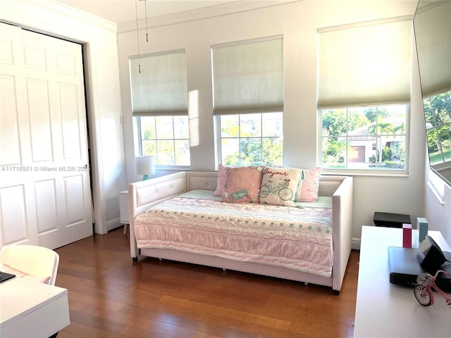 bedroom with ornamental molding and dark wood-type flooring