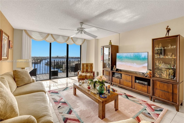 living area with ceiling fan, a textured ceiling, light tile patterned flooring, and floor to ceiling windows