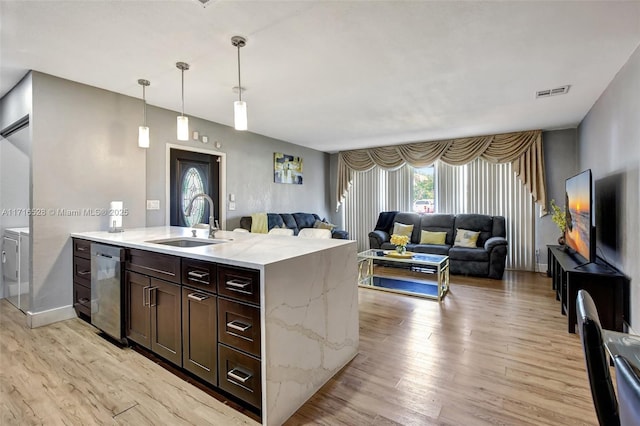 kitchen with dark brown cabinets, washer and clothes dryer, sink, dishwasher, and hanging light fixtures