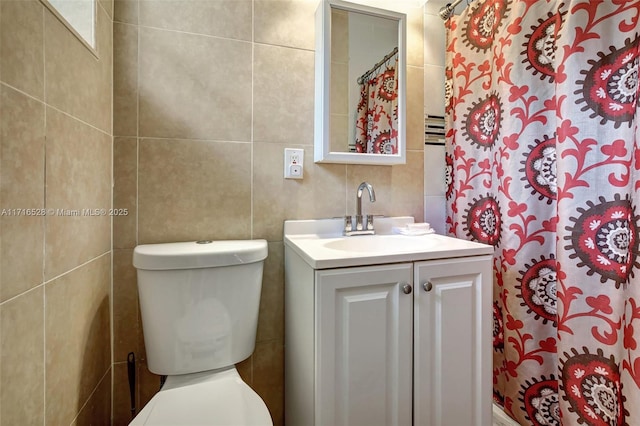 bathroom featuring vanity, tile walls, and toilet