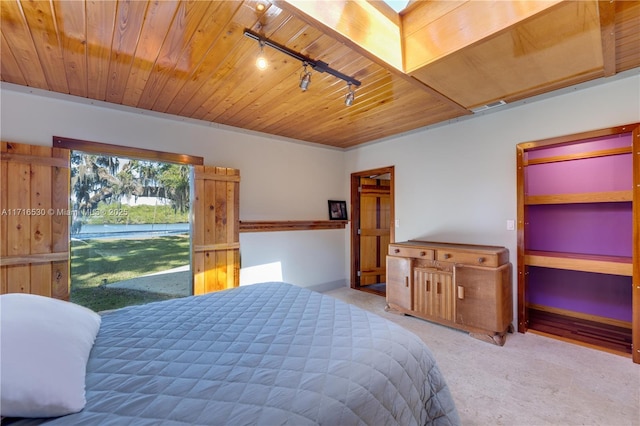 carpeted bedroom featuring track lighting, wood ceiling, and a skylight