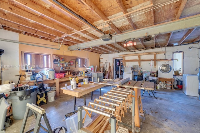 miscellaneous room with concrete flooring, washer / dryer, and a workshop area