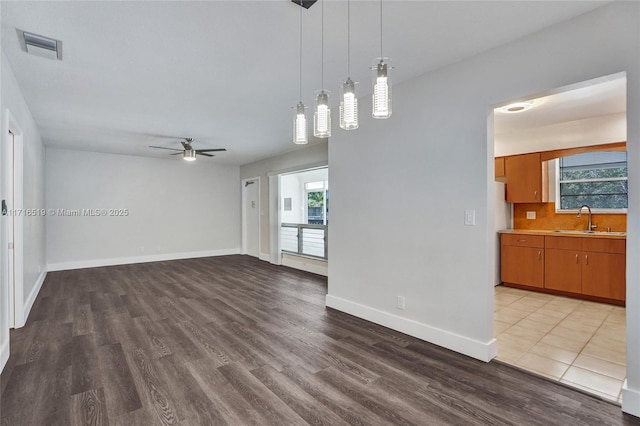 spare room featuring wood finished floors, a sink, visible vents, and a healthy amount of sunlight