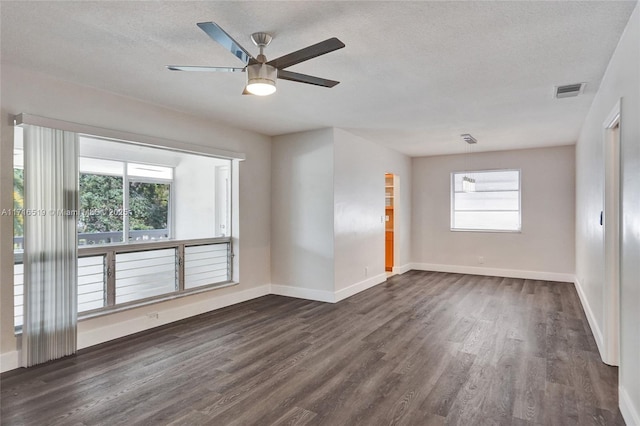 unfurnished room featuring visible vents, a textured ceiling, baseboards, and dark wood-type flooring