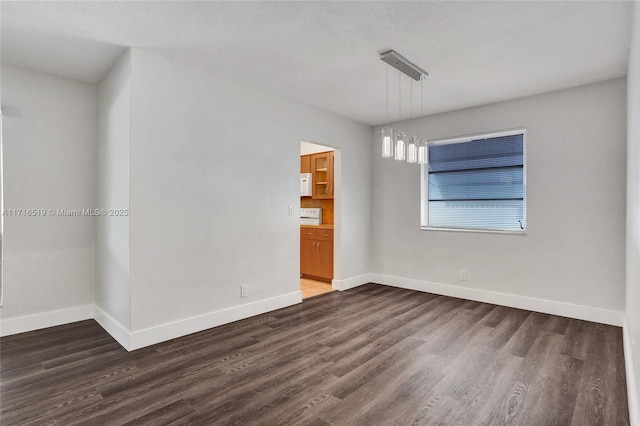 unfurnished room with dark wood-style flooring and baseboards