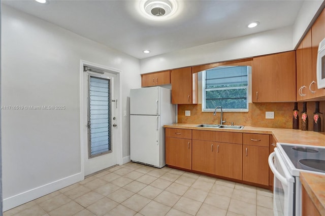 kitchen featuring white appliances, tasteful backsplash, light countertops, and a sink