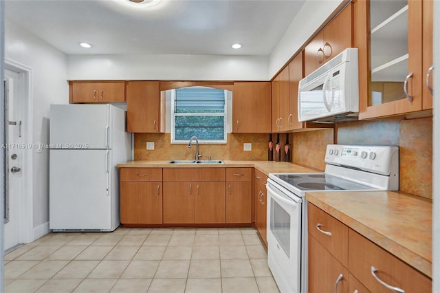 kitchen featuring white appliances, light countertops, a sink, and backsplash