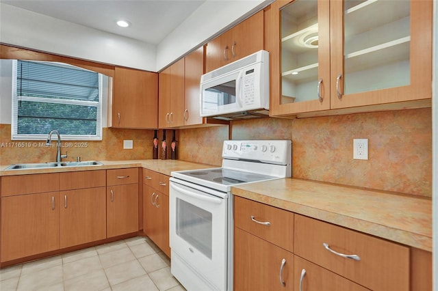 kitchen with light countertops, white appliances, light tile patterned flooring, and a sink