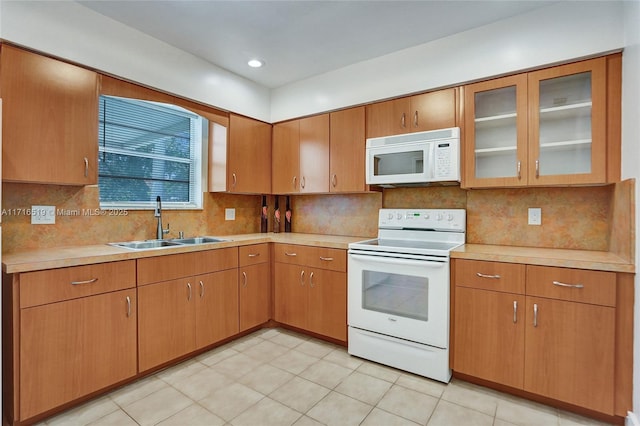 kitchen featuring white appliances, backsplash, light countertops, and a sink