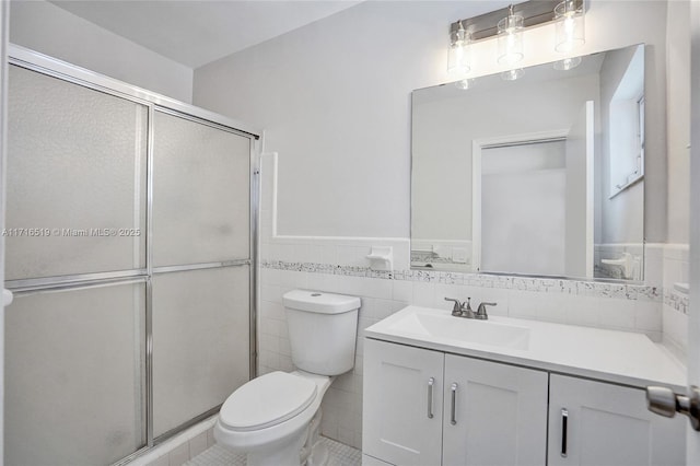 full bathroom with tile walls, toilet, a shower stall, and vanity