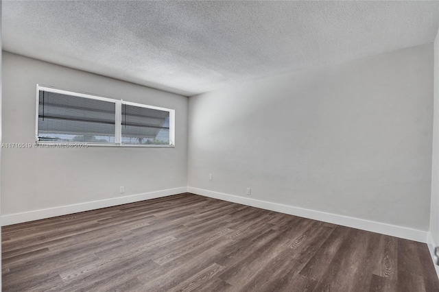 spare room featuring baseboards and dark wood-style flooring