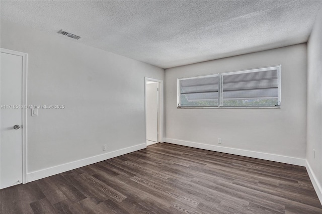 spare room with visible vents, a textured ceiling, baseboards, and wood finished floors