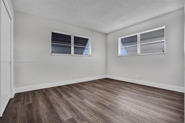 spare room featuring a textured ceiling, wood finished floors, and baseboards