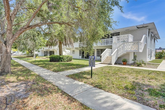 view of front of home with a front yard, a wooden deck, and stairs