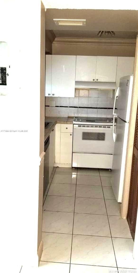 kitchen with light tile patterned floors, decorative backsplash, white cabinetry, and white appliances