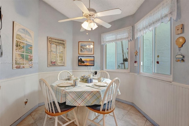 tiled dining room with ceiling fan and a textured ceiling