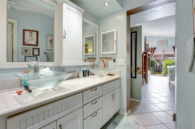 bathroom with tile patterned floors, vanity, a textured ceiling, and vaulted ceiling