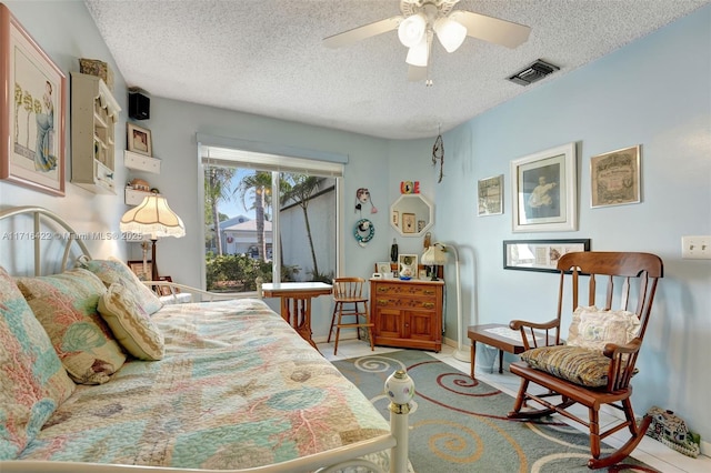 bedroom with ceiling fan, light tile patterned floors, and a textured ceiling