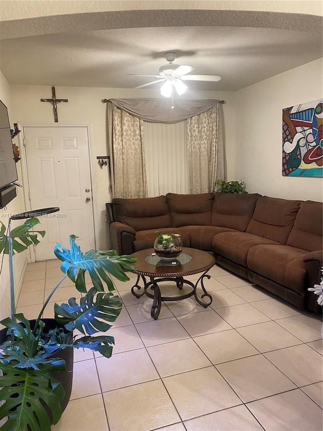 living room featuring ceiling fan, light tile patterned flooring, and a textured ceiling