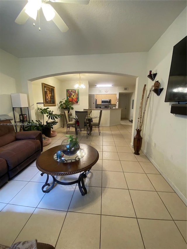 tiled living room featuring ceiling fan with notable chandelier